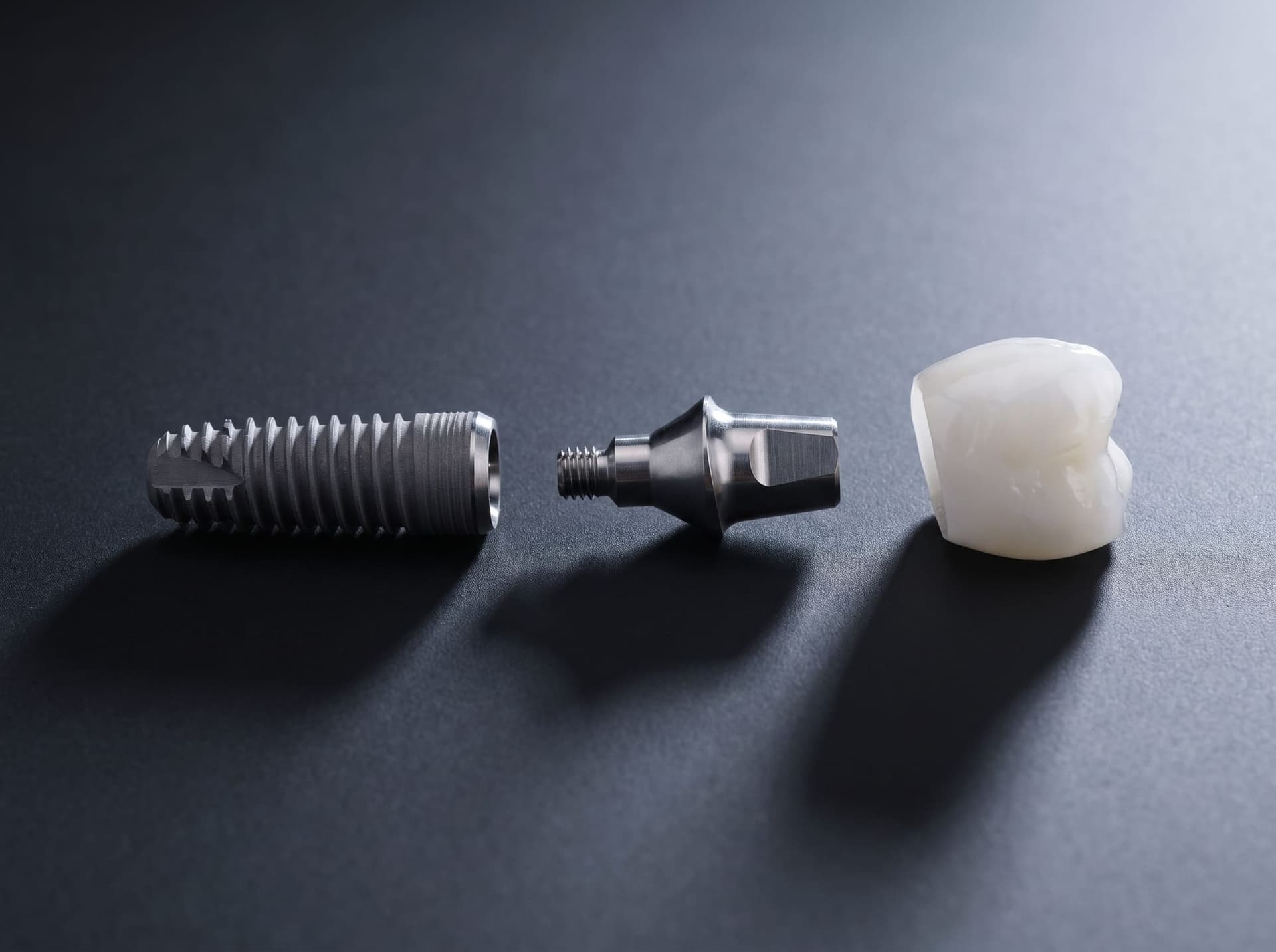 Les trois composants d'un implant dentaire : vis en titane, pilier et couronne